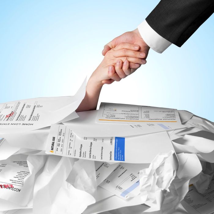 A hand pulling another hand out from a pile of bills