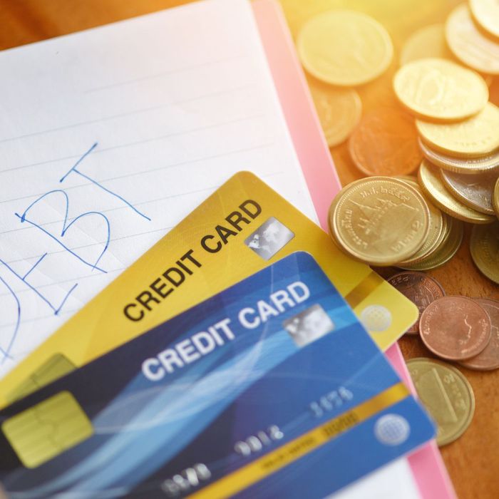 Credit cards on top of a paper that says debt with coins to the side