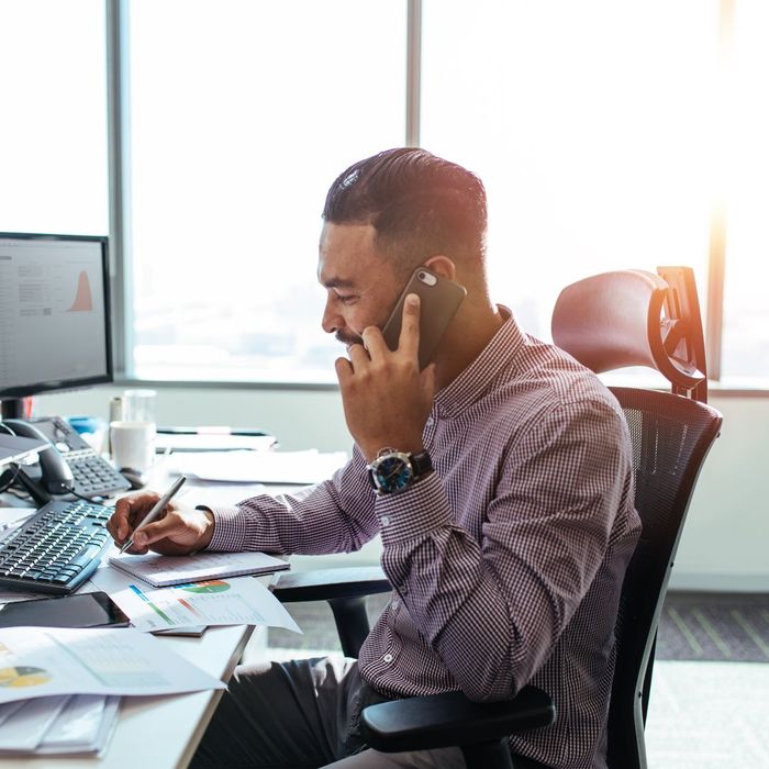 man on phone call with a lot of papers on desk